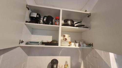 une cuisine avec des étagères blanches avec des tasses et des appareils électroménagers dans l'établissement Petit studio promenade des Anglais, à Nice