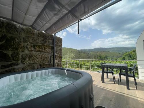 a hot tub on a balcony with a table at Casa da Garrafeira - Quinta da Portela in Terras de Bouro
