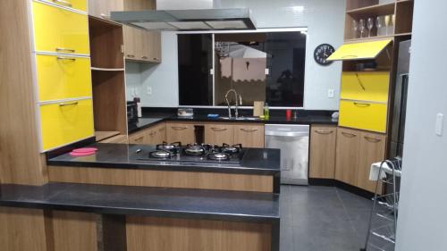 a kitchen with yellow cabinets and a stove in it at Pousada do Bosque-Hostel in Rio Branco