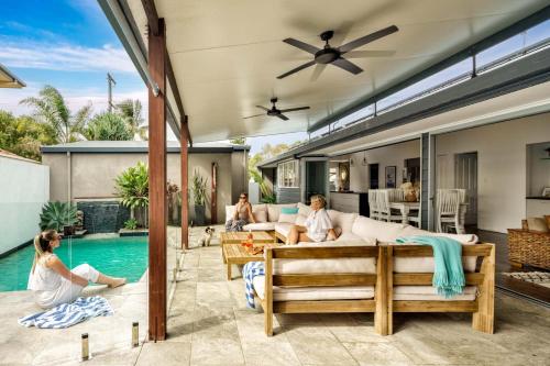 a group of people sitting on a patio next to a swimming pool at Pet Friendly House Opposite Bokarina Beach in Kawana Waters