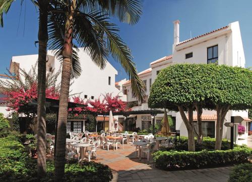une terrasse avec des tables et des chaises devant un bâtiment dans l'établissement MarSureño, à Los Cristianos