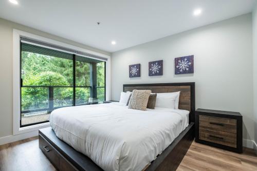 a bedroom with a large bed and a large window at Powderhorn 205 by Outpost Whistler in Whistler