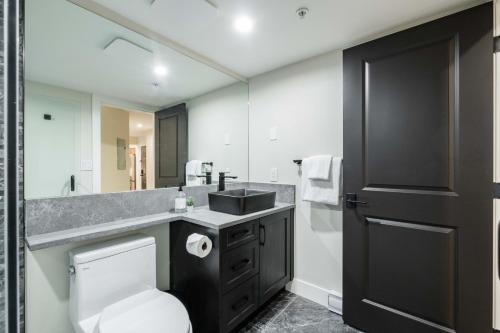 a bathroom with a toilet and a sink and a mirror at Powderhorn 205 by Outpost Whistler in Whistler