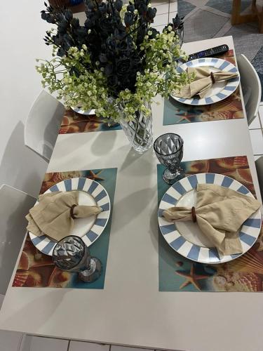 a white table with plates and a vase of flowers at Life Flats Temporada com Bela vista à 50m da Praia in Recife