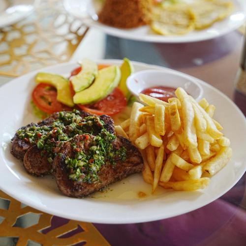 a plate of food with steak and french fries at Hotel Isla Real in Tierra Bomba