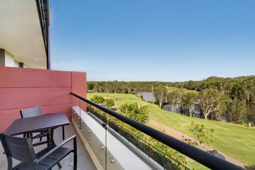 a balcony with a table and a view of a golf course at Mercure Kooindah Waters Central Coast in Wyong