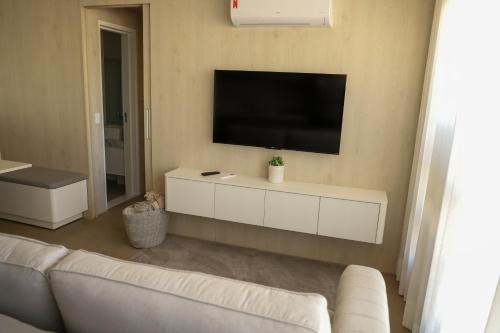 a living room with a white couch and a flat screen tv at Ap de Alto padrão perto da feira da lua in Goiânia