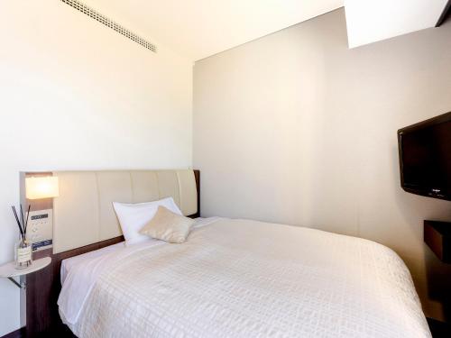 a bedroom with a white bed and a flat screen tv at Hotel Gracery Sapporo in Sapporo