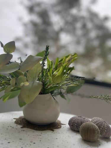 a white vase with flowers in it on a table at White Beach Retreat - Luxurious Water Views in White Beach
