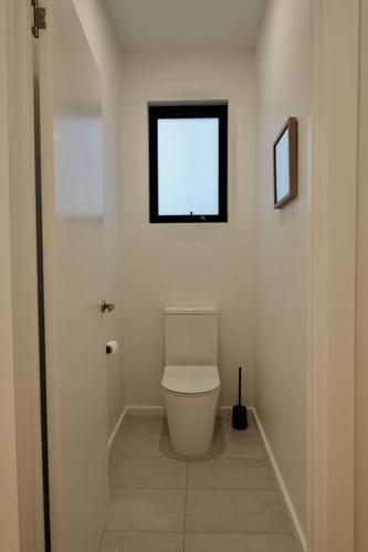 a white bathroom with a toilet and a window at White Beach Retreat - Luxurious Water Views in White Beach