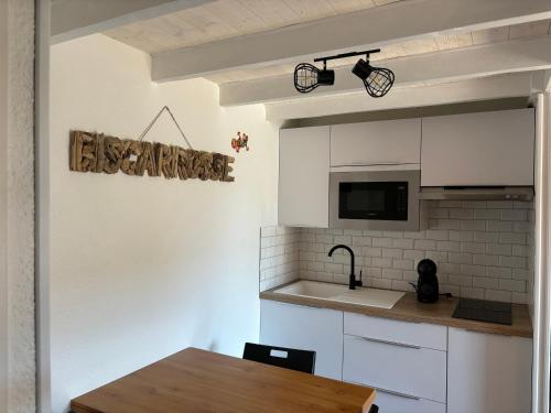 une cuisine avec des armoires blanches et une table en bois dans l'établissement Maison 2 chambres à Biscarrosse Plage, à deux pas de la mer, avec terrasse, parking et ménage inclus - FR-1-319-438, à Biscarrosse