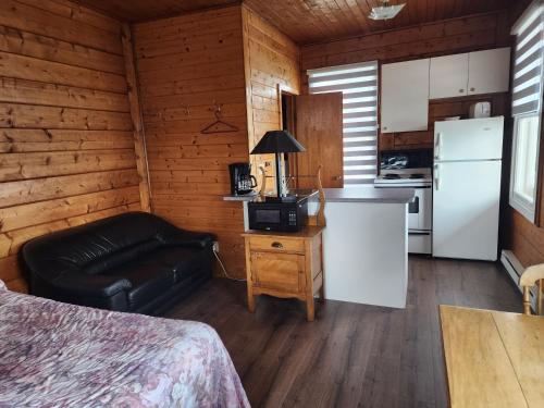 a room with a bed and a kitchen in a cabin at Motel et Chalets Bo-Fleuve Evangeline in Saint-Siméon