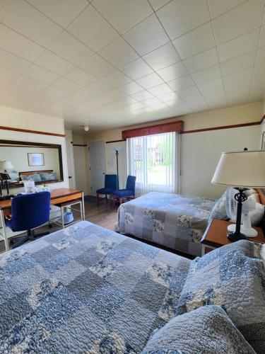 a hotel room with two beds and a desk at Motel et Chalets Bo-Fleuve Evangeline in Saint-Siméon