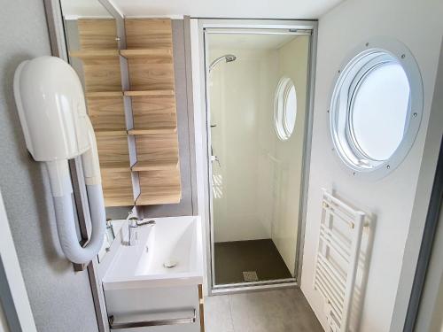 une petite salle de bain avec un lavabo et une douche dans l'établissement Mobil-home Grand Confort à 200m de la plage avec piscine chauffée, 4 pers, terrasse, parking - FR-1-361A-21, à Jullouville