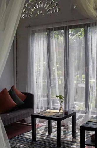 a living room with a couch and a table in front of a window at Langkawi Rouhi Retreats by uBook in Kuah