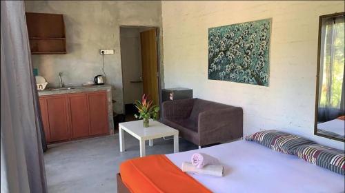 a room with a bed and a chair and a kitchen at Langkawi Rouhi Retreats by uBook in Kuah