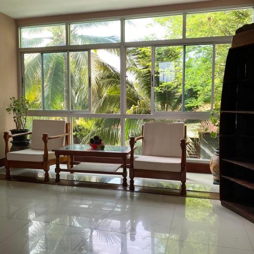 a room with two chairs and a table in front of a large window at Maikaew Damnoen Resort in Damnoen Saduak