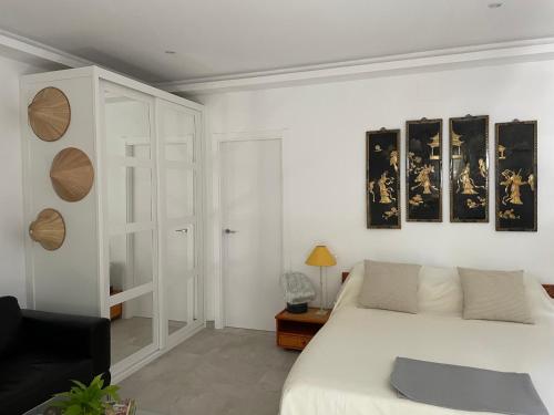 a bedroom with a white bed and a black chair at Finca vista de la roca in Estepona