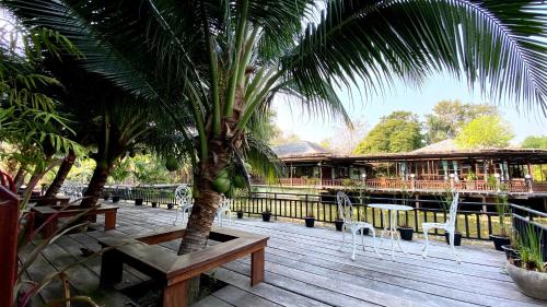 a wooden deck with palm trees and a building at Maikaew Damnoen Resort in Damnoen Saduak