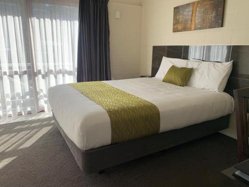 a large bed in a hotel room with windows at Admirals Motor Inn in Nelson