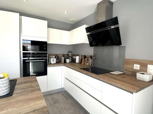 une cuisine avec des armoires blanches et une télévision à écran plat dans l'établissement Maison de vacances avec jardin clos, à proximité de la plage de Barbâtre, 6 couchages - FR-1-224B-227, à Barbâtre