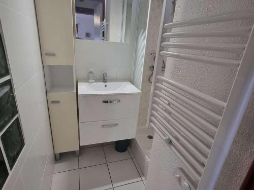 une salle de bain blanche avec un lavabo et un miroir dans l'établissement Charmante Villa T3 avec Piscine, Terrasse et Parking pour 6 Personnes à Port Barcarès - FR-1-81-619, au Barcarès