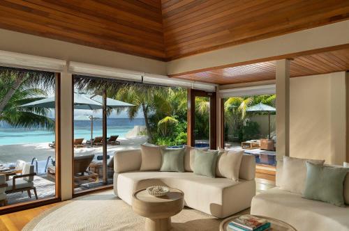 a living room with a couch and a view of the ocean at Huvafen Fushi Maldives in North Male Atoll