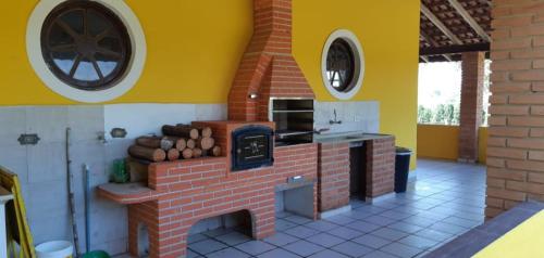 a kitchen with a brick fireplace with a stove at Belíssima Chácara de Alto Padrão em Boituva in Boituva