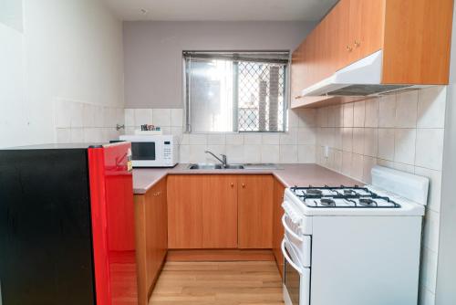 a kitchen with a white stove and a red refrigerator at Apartment 3 Burswood in Perth