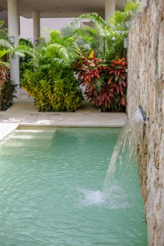 a water fountain in a pool in a building at Catamaran Condo in Kam Na Ha in Bacalar
