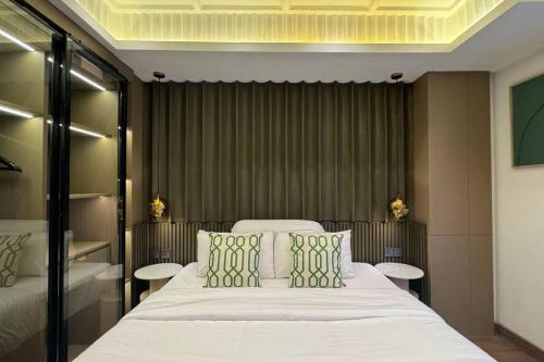 a bedroom with a large white bed with green pillows at Earthy Modern 2 Bedrooms Apt in Sleman