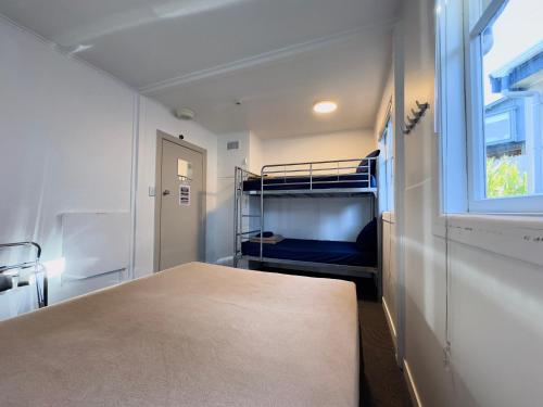 a small room with a bunk bed and a window at Waiheke Backpackers Hostel in Onetangi