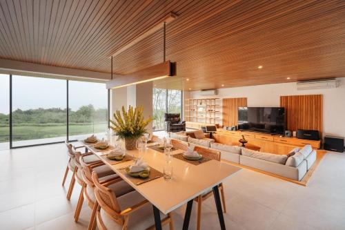 a dining room with a long table and a couch at Villa Avocagolf Uluwatu by Nakula in Uluwatu