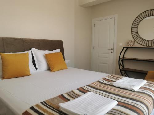 a bed with orange and white pillows and a mirror at Amber drop with a pool in Ravda