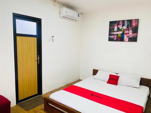 a bedroom with a bed with a red blanket on it at RedDoorz Syariah Near Wisata Durensewu Pandaan in Jetak