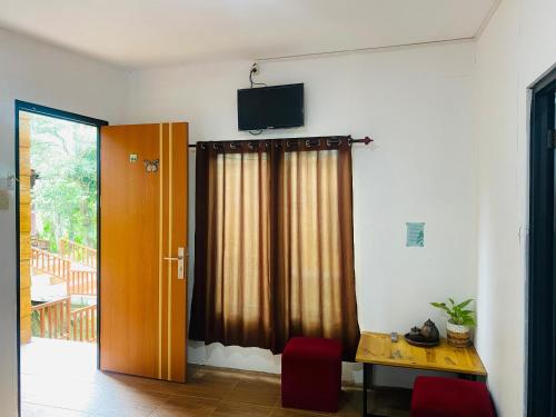 a room with a table and a television on the wall at RedDoorz Syariah Near Wisata Durensewu Pandaan in Jetak