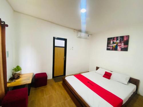 a bedroom with a bed and a table and a door at RedDoorz Syariah Near Wisata Durensewu Pandaan in Jetak
