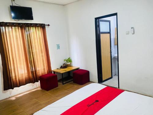 a bedroom with a bed and a television and a mirror at RedDoorz Syariah Near Wisata Durensewu Pandaan in Jetak