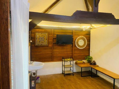 a bathroom with a sink and a tv on a wall at RedDoorz Syariah Near Wisata Durensewu Pandaan in Jetak
