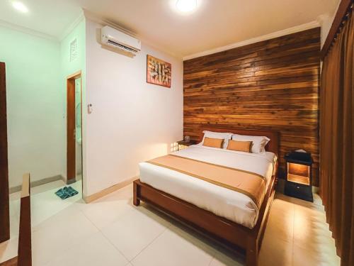 a bedroom with a bed and a wooden wall at Rostika Hotel Sekumpul in Buleleng