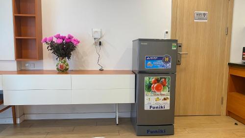 a refrigerator next to a counter with a vase of flowers at Era Cozy Apartment in Hanoi