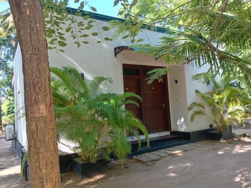 a house with a wooden door and some palm trees at Kings Village Sigiriya in Sigiriya