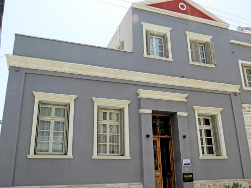 a gray building with white windows and a door at Axilleion Boutique Hotel in Ermoupoli