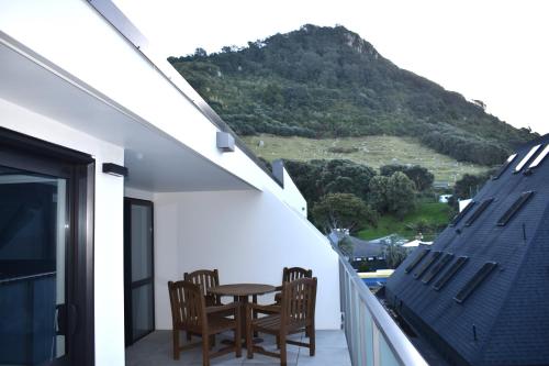 a balcony with a table and chairs and a mountain at 6 on Adams in Mount Maunganui