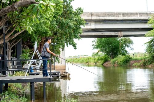 a man standing on a dock holding a fishing line at The Great Residence Suvarnabhumi Airport in Lat Krabang