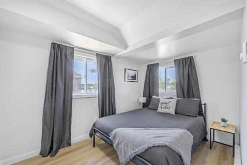 ein Schlafzimmer mit einem Bett und zwei Fenstern in der Unterkunft Riverfront Cottages in Wasaga Beach