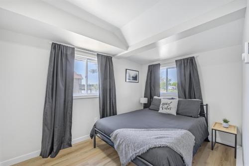 a bedroom with a bed and two windows at Riverfront Cottages in Wasaga Beach