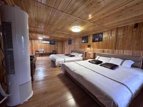 two beds in a room with wooden walls and wooden floors at Bridge View Boutique Guesthouse 望桥楼精品民宿 in Sanjiang