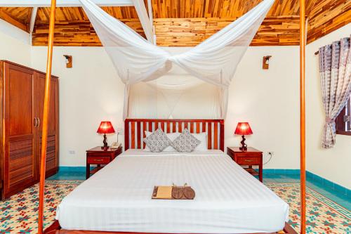 a bedroom with a canopy bed with a purse on it at Phu Quoc Eco Beach Resort in Phú Quốc