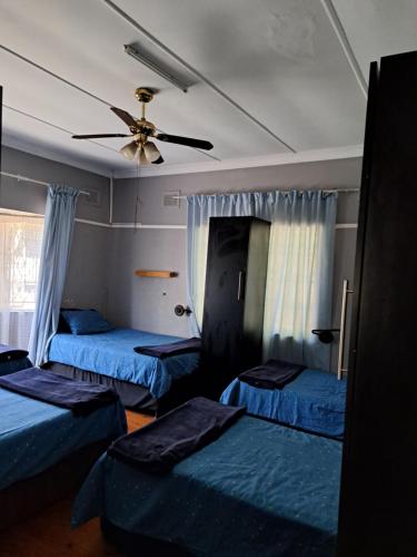 a room with three beds and a ceiling fan at PMB Backpackers Lodge in Pietermaritzburg